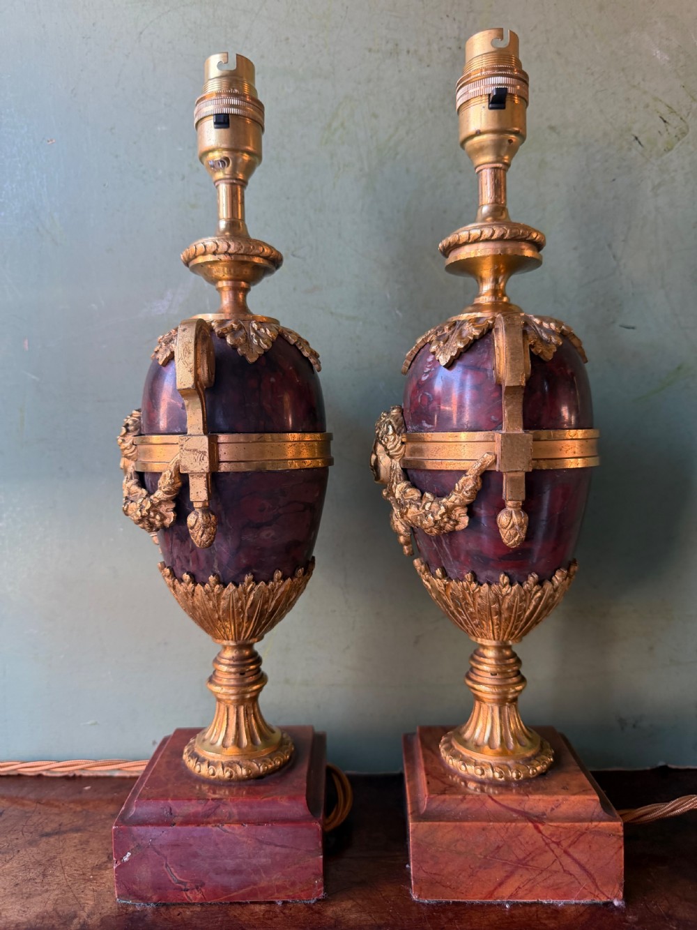A pair of late nineteenth-century French rouge marble table lamps shaped as urns with gilt bronze mounts and square pedestal bases. View III