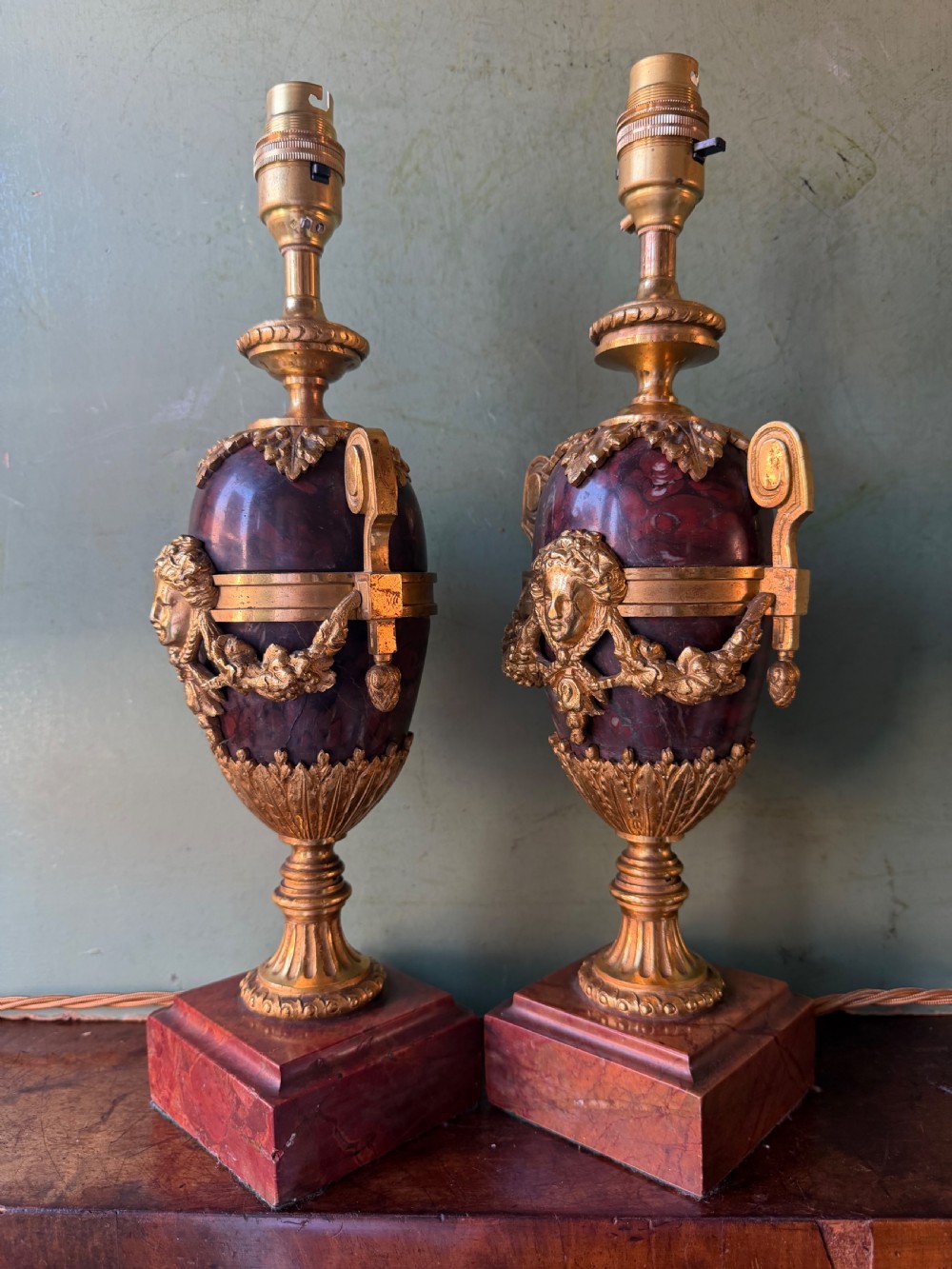 A pair of late nineteenth-century French rouge marble table lamps shaped as urns with gilt bronze mounts and square pedestal bases. View IV