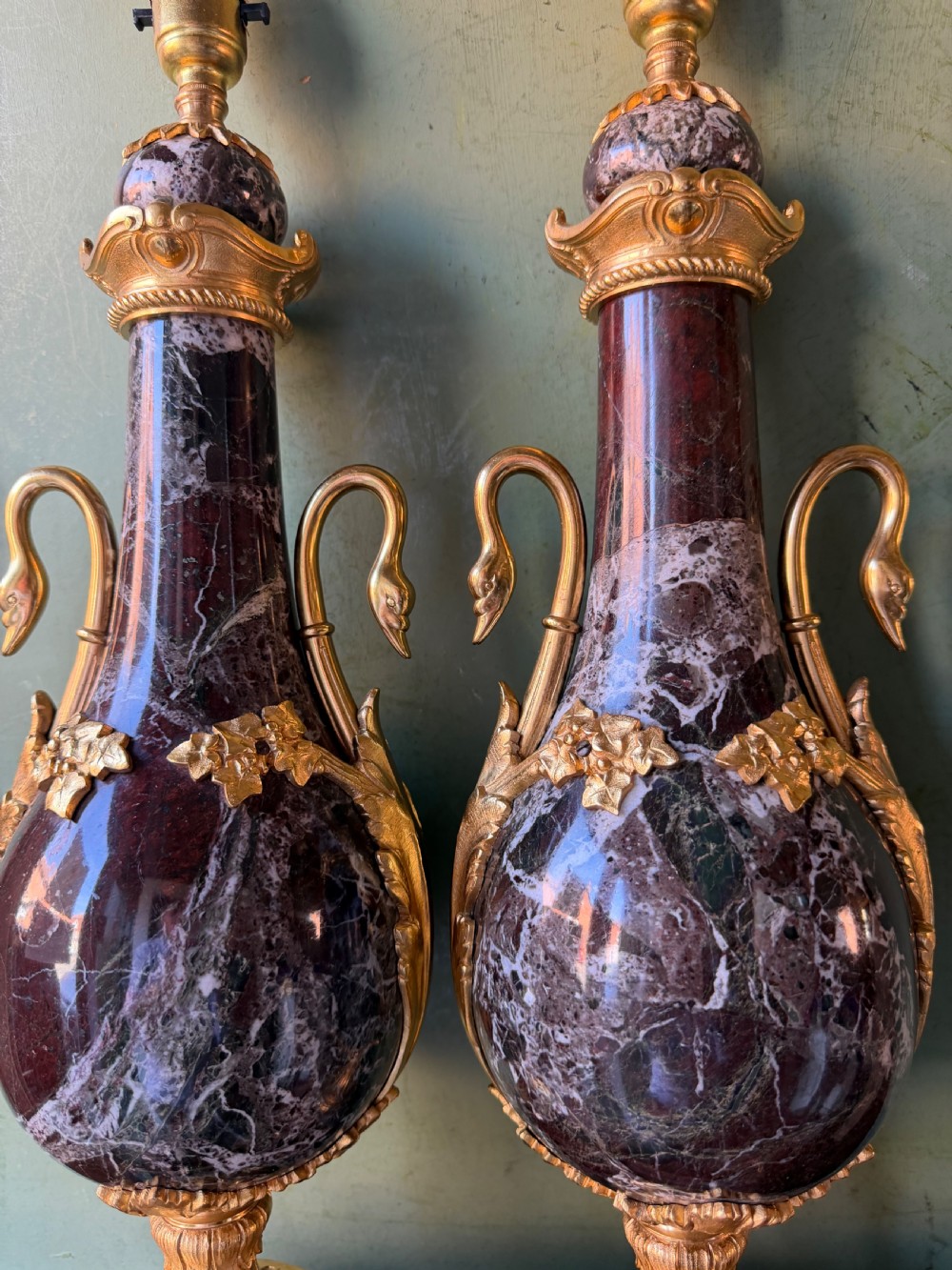 A pair of urn-shaped burgundy marble table lamps featuring gilded bronze swan handles and square pedestals. View II