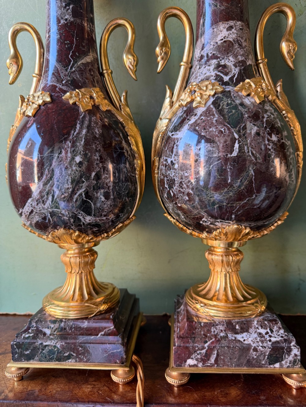 A pair of urn-shaped burgundy marble table lamps featuring gilded bronze swan handles and square pedestals. View III