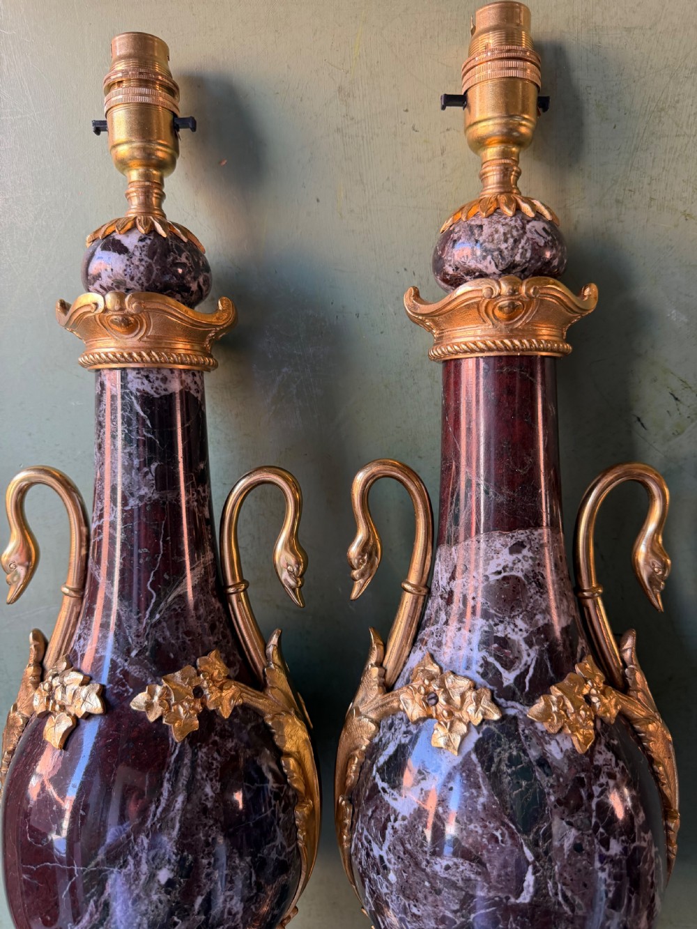 A pair of urn-shaped burgundy marble table lamps featuring gilded bronze swan handles and square pedestals. View V