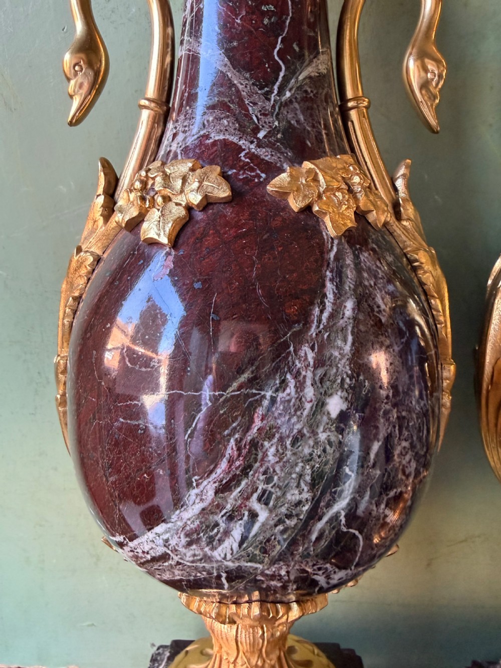 A pair of urn-shaped burgundy marble table lamps featuring gilded bronze swan handles and square pedestals. View X