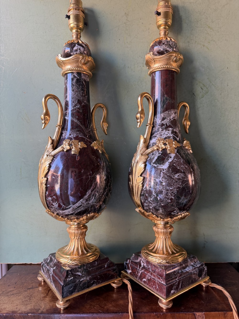 A pair of urn-shaped burgundy marble table lamps featuring gilded bronze swan handles and square pedestals. View XIX