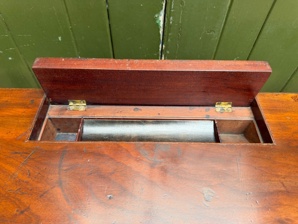 Early 19th-century George IV mahogany writing table featuring a long frieze drawer with brass rosette handles and reeded turned legs on castors. View IV