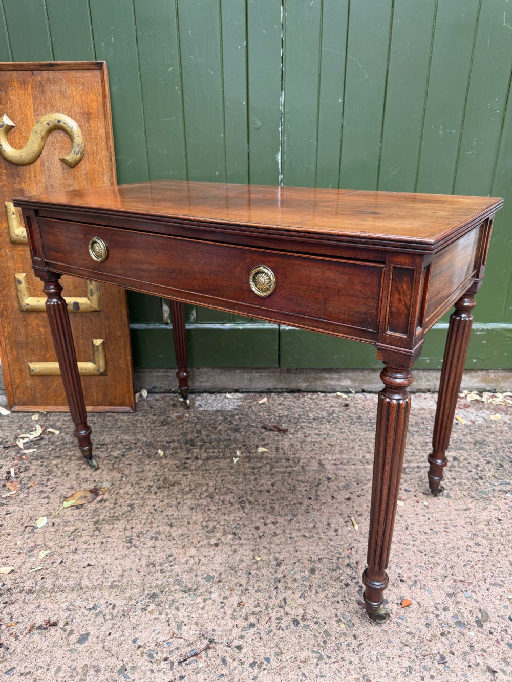 Early 19th-century George IV mahogany writing table featuring a long frieze drawer with brass rosette handles and reeded turned legs on castors. View V