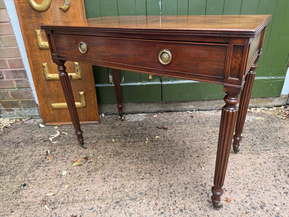 Early 19th-century George IV mahogany writing table featuring a long frieze drawer with brass rosette handles and reeded turned legs on castors. View VI