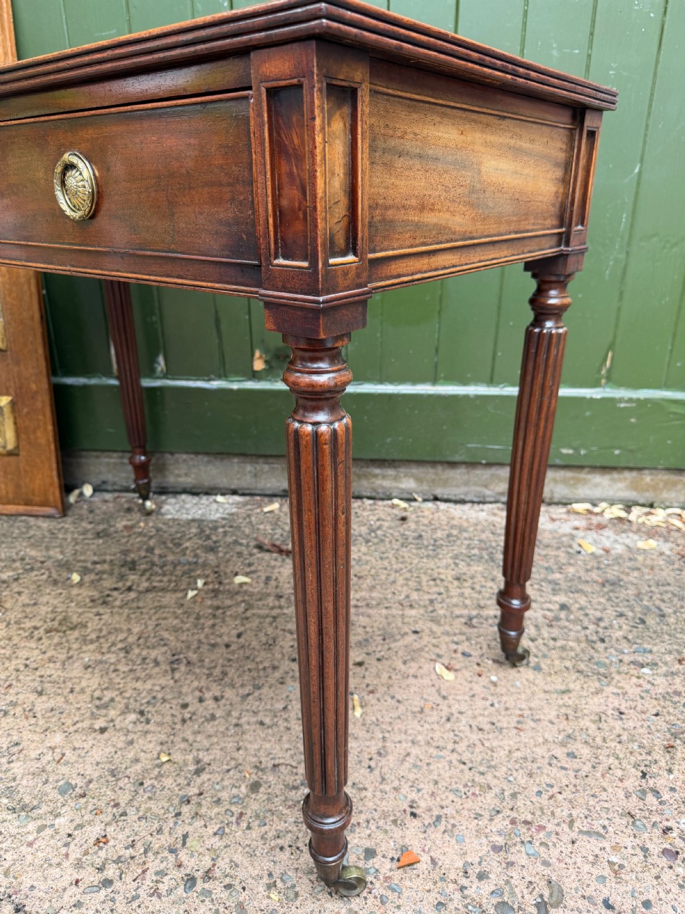 Early 19th-century George IV mahogany writing table featuring a long frieze drawer with brass rosette handles and reeded turned legs on castors. View VII
