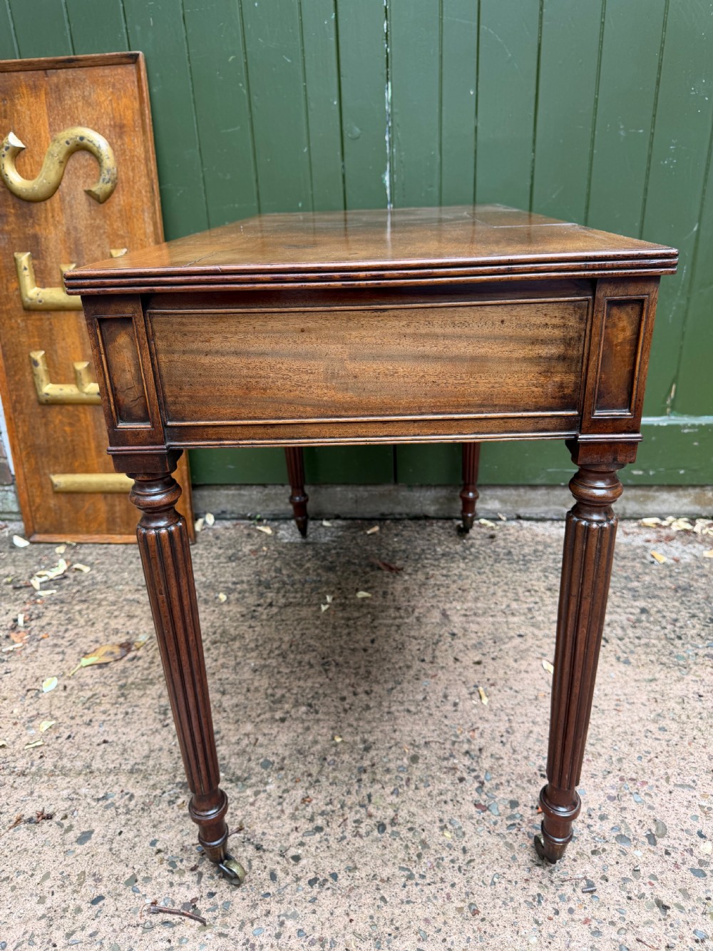 Early 19th-century George IV mahogany writing table featuring a long frieze drawer with brass rosette handles and reeded turned legs on castors. View VIII