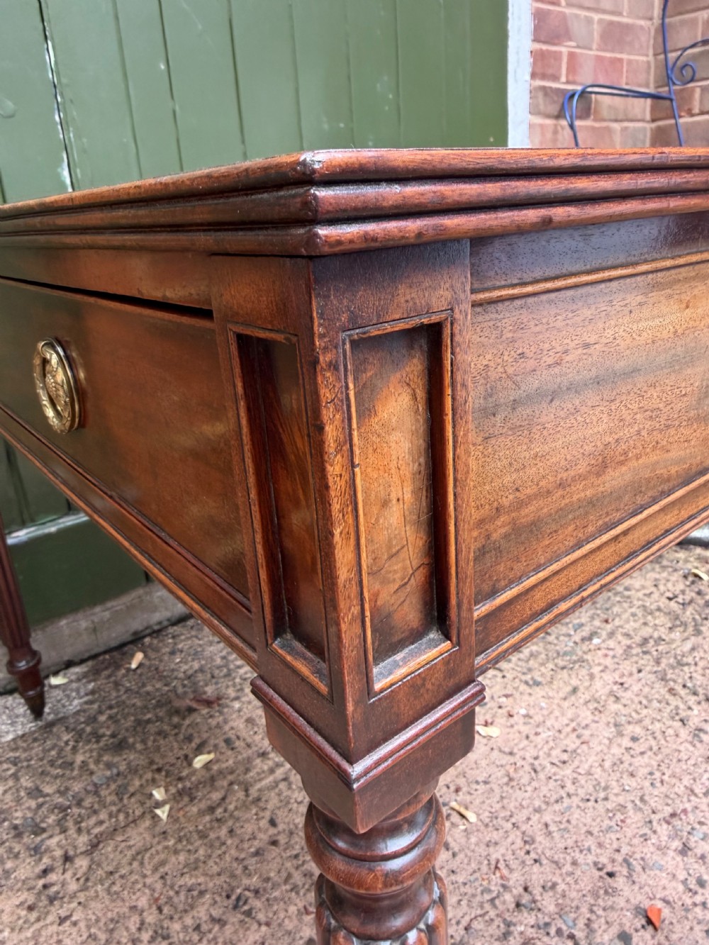 Early 19th-century George IV mahogany writing table featuring a long frieze drawer with brass rosette handles and reeded turned legs on castors. View X