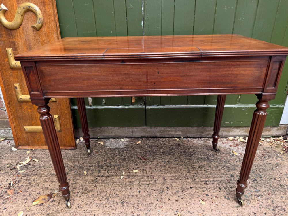 Early 19th-century George IV mahogany writing table featuring a long frieze drawer with brass rosette handles and reeded turned legs on castors. View XI