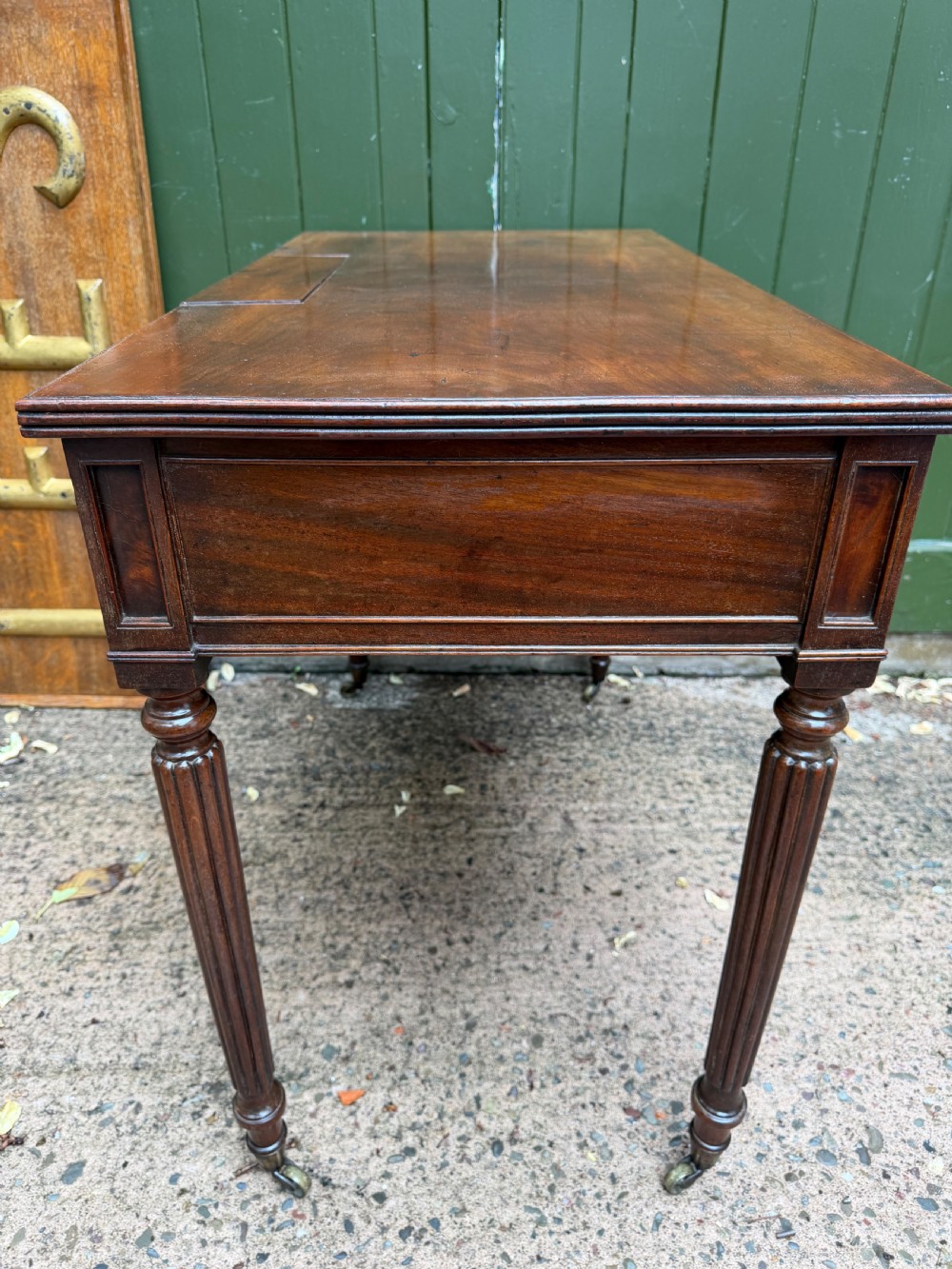 Early 19th-century George IV mahogany writing table featuring a long frieze drawer with brass rosette handles and reeded turned legs on castors. View XVI