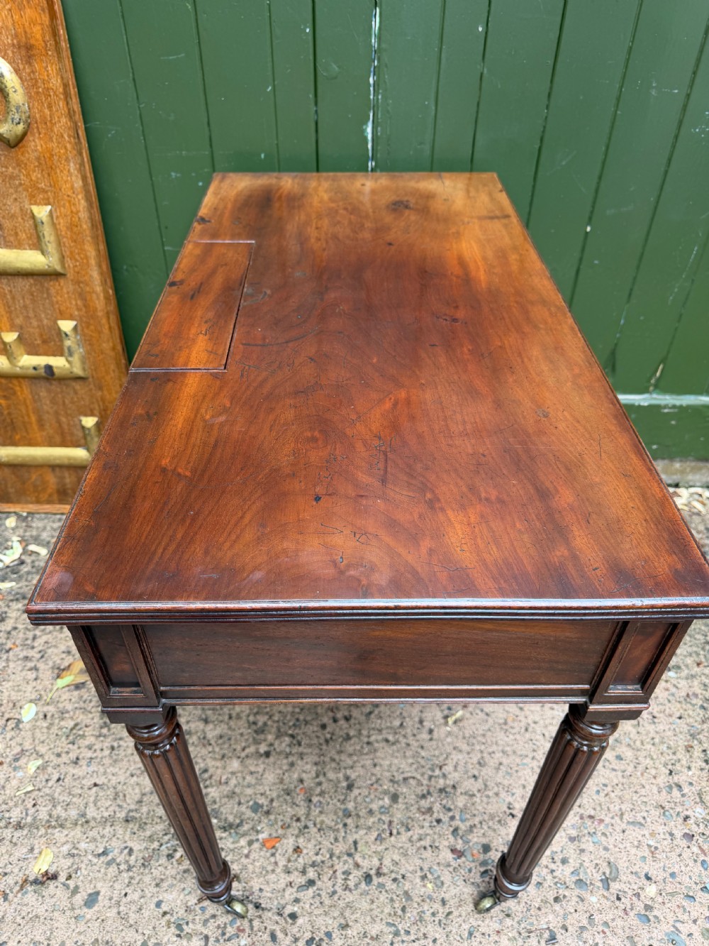 Early 19th-century George IV mahogany writing table featuring a long frieze drawer with brass rosette handles and reeded turned legs on castors. View XVII