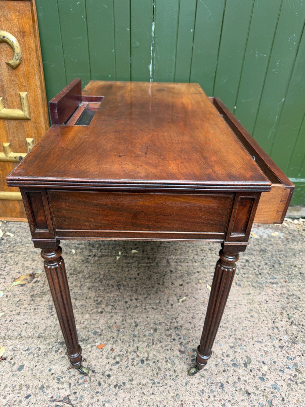 Early 19th-century George IV mahogany writing table featuring a long frieze drawer with brass rosette handles and reeded turned legs on castors. View XVIII