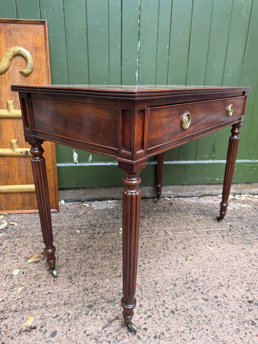 Early 19th-century George IV mahogany writing table featuring a long frieze drawer with brass rosette handles and reeded turned legs on castors. View XIX