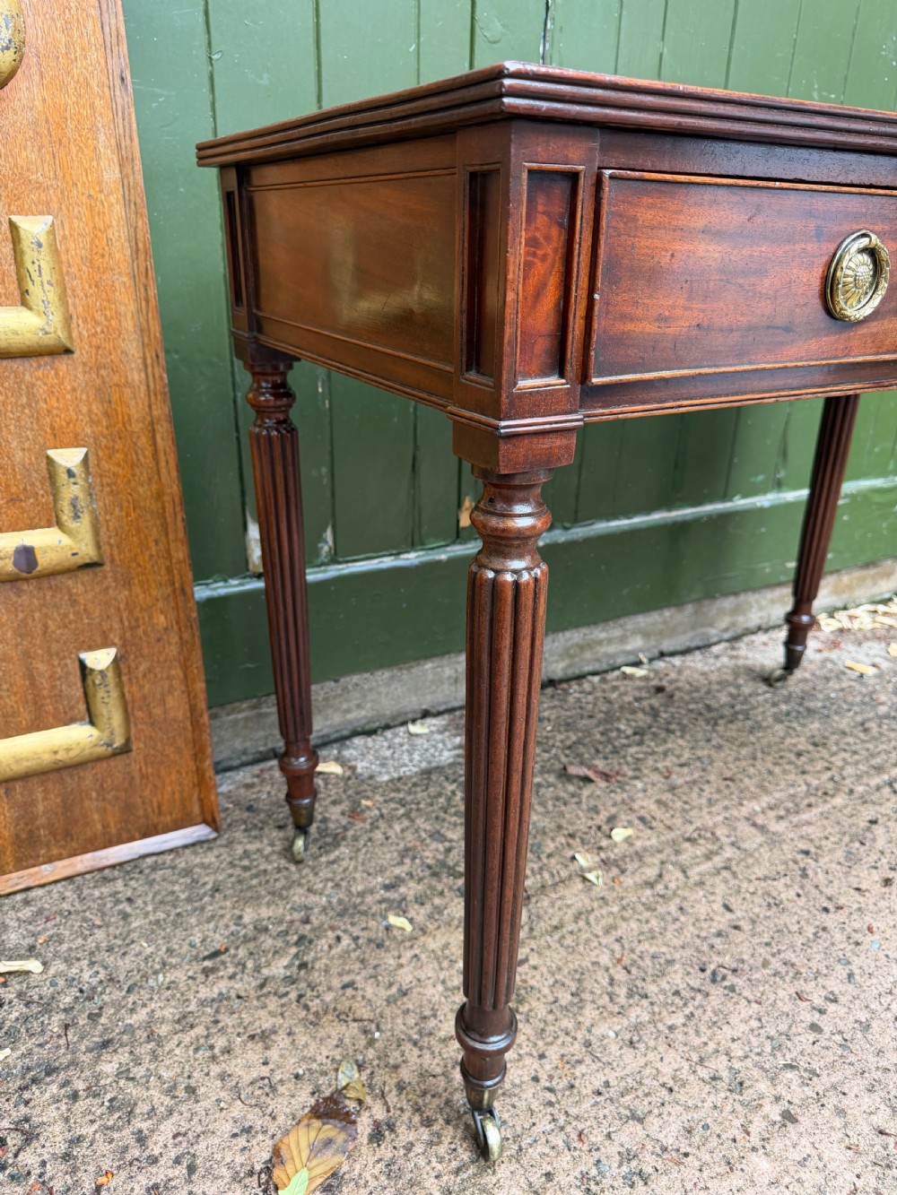 Early 19th-century George IV mahogany writing table featuring a long frieze drawer with brass rosette handles and reeded turned legs on castors. View XXI