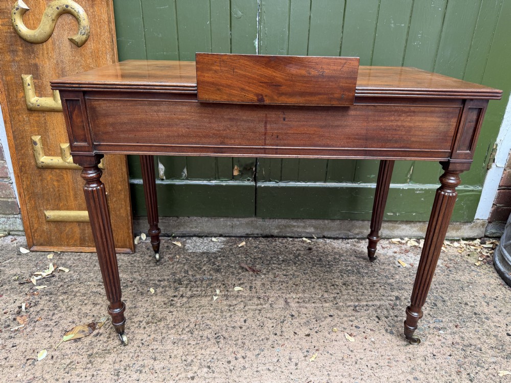 Early 19th-century George IV mahogany writing table featuring a long frieze drawer with brass rosette handles and reeded turned legs on castors. View XXII