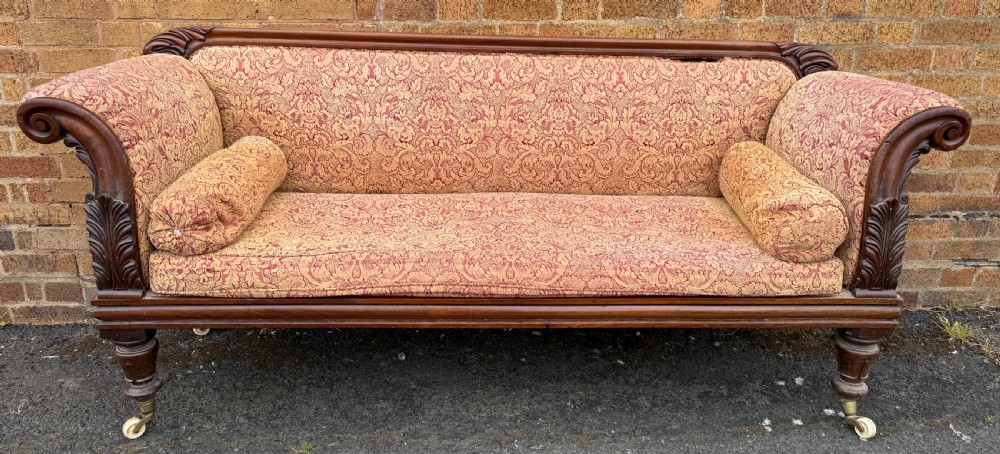 Early 19th-century William IV carved mahogany scroll-end sofa upholstered in red and gold patterned damask with matching bolster cushions. View III