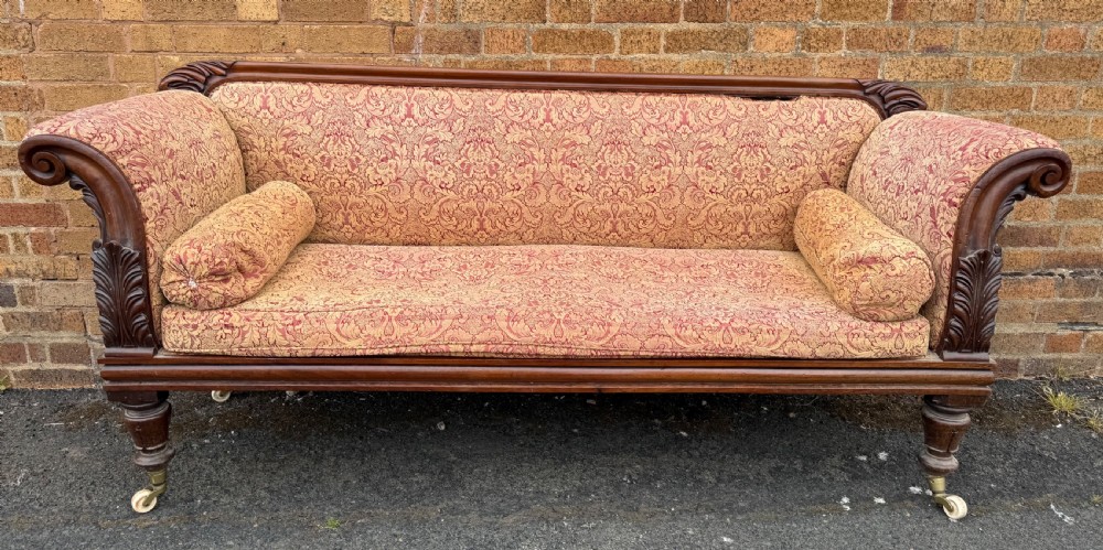 Early 19th-century William IV carved mahogany scroll-end sofa upholstered in red and gold patterned damask with matching bolster cushions. View VII