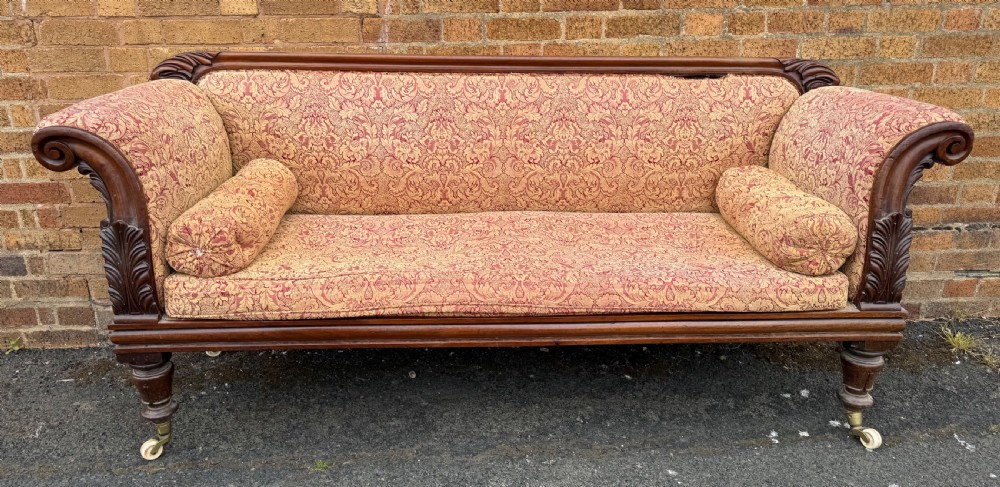 Early 19th-century William IV carved mahogany scroll-end sofa upholstered in red and gold patterned damask with matching bolster cushions. View X