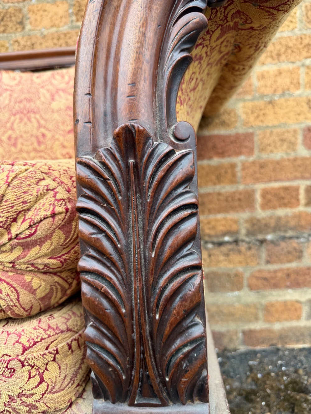 Early 19th-century William IV carved mahogany scroll-end sofa upholstered in red and gold patterned damask with matching bolster cushions. View XII