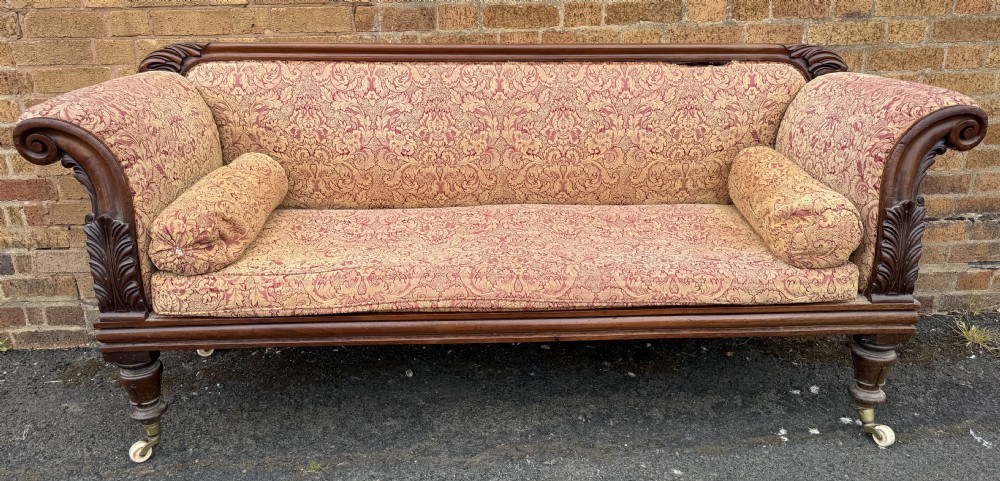 Early 19th-century William IV carved mahogany scroll-end sofa upholstered in red and gold patterned damask with matching bolster cushions. View XIV