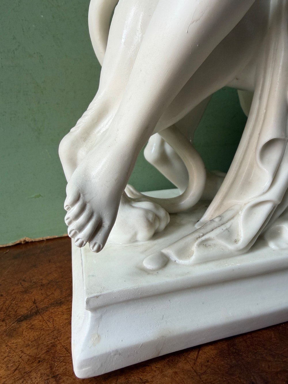A white Parian porcelain Neoclassical sculpture depicting a reclining female figure mounted on the back of a panther on a rectangular plinth. View IV