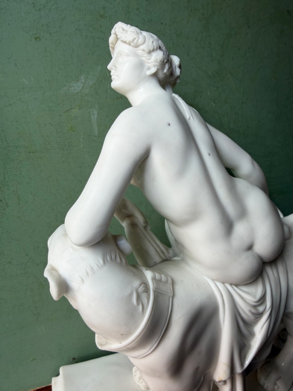 A white Parian porcelain Neoclassical sculpture depicting a reclining female figure mounted on the back of a panther on a rectangular plinth. View IX