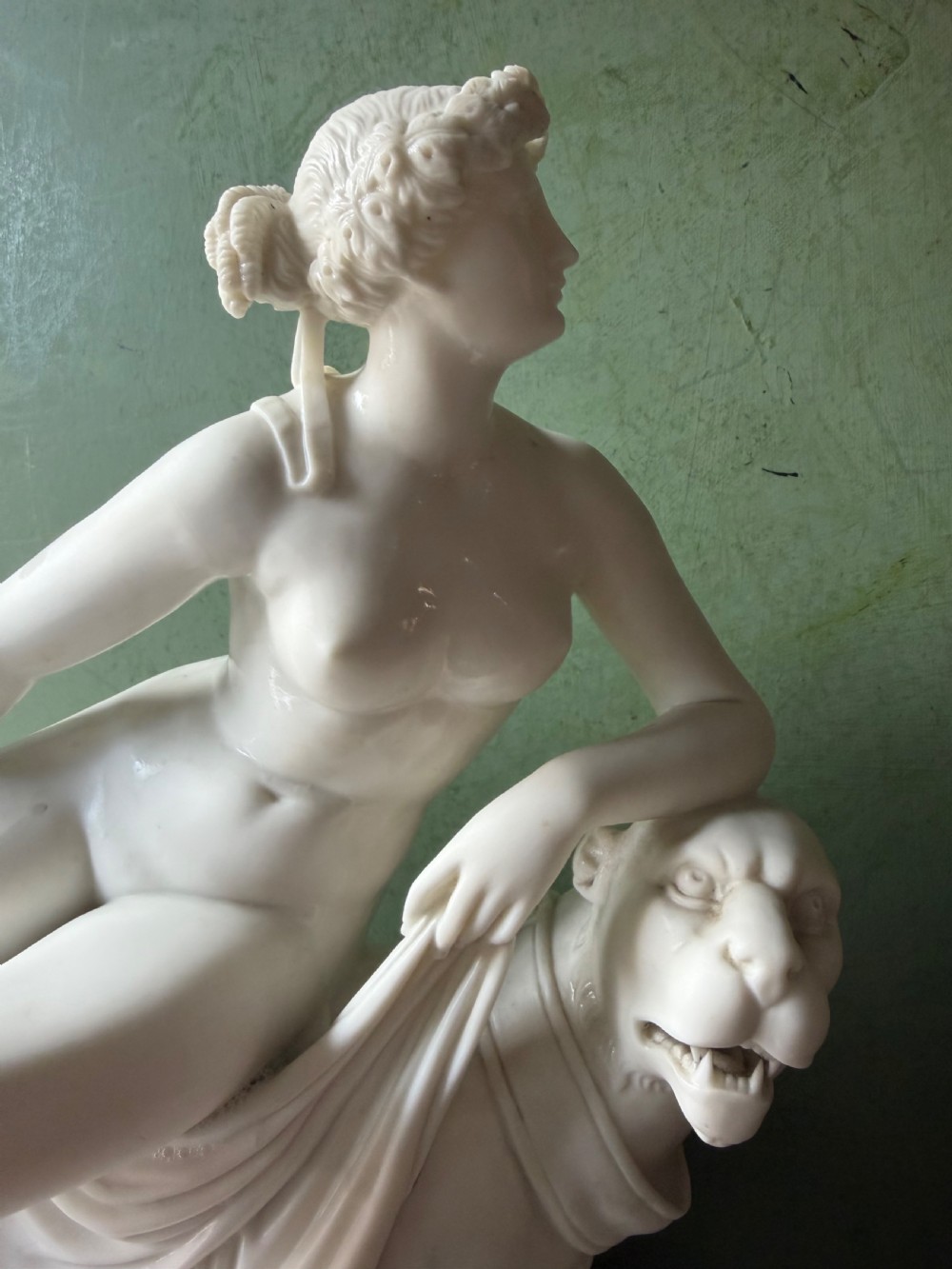 A white Parian porcelain Neoclassical sculpture depicting a reclining female figure mounted on the back of a panther on a rectangular plinth. View XI