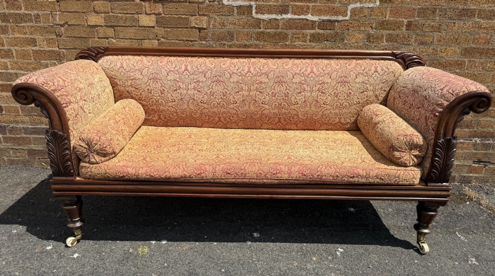Early 19th-century William IV carved mahogany scroll-end sofa upholstered in red and gold patterned damask with matching bolster cushions. View VIII