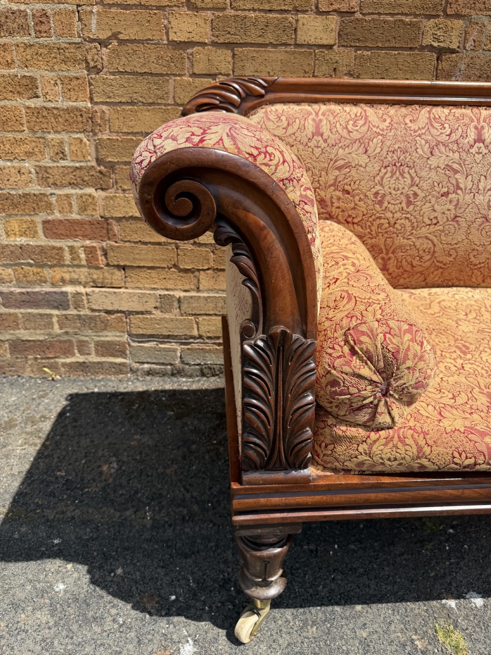 Early 19th-century William IV carved mahogany scroll-end sofa upholstered in red and gold patterned damask with matching bolster cushions. View XV