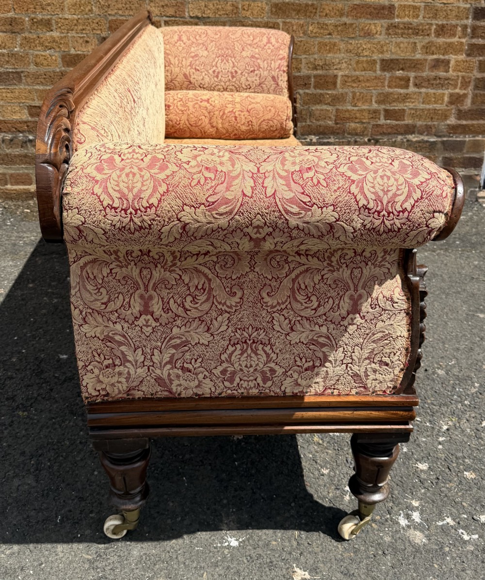 Early 19th-century William IV carved mahogany scroll-end sofa upholstered in red and gold patterned damask with matching bolster cushions. View XVI