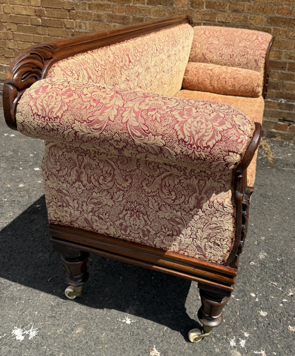 Early 19th-century William IV carved mahogany scroll-end sofa upholstered in red and gold patterned damask with matching bolster cushions. View XVII