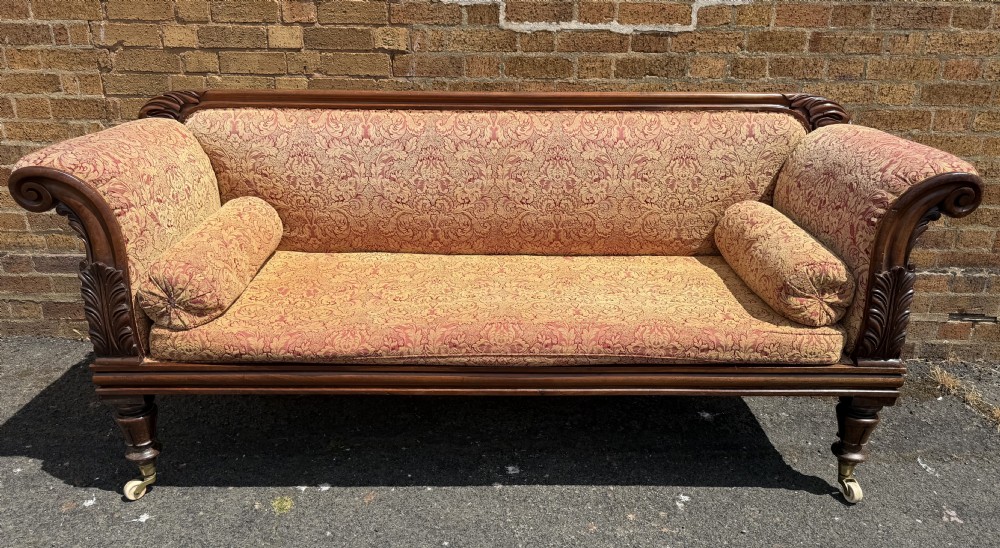 Early 19th-century William IV carved mahogany scroll-end sofa upholstered in red and gold patterned damask with matching bolster cushions. View XXI