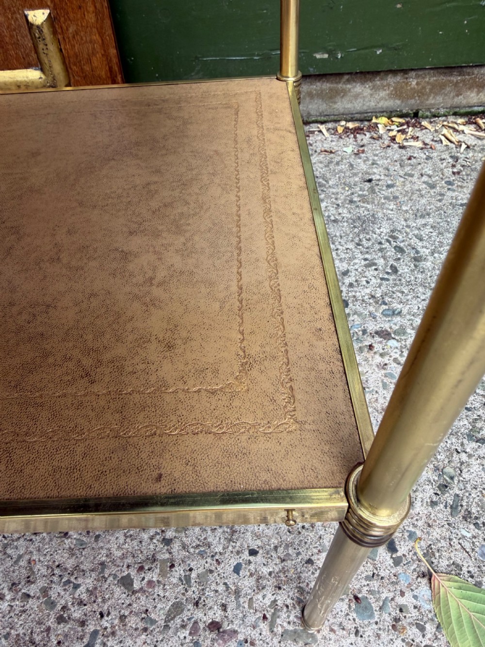 A pair of early twentieth-century two-tier lacquered brass etagere tables featuring inset tan tooled leather tops and turned brass corner posts. View VII