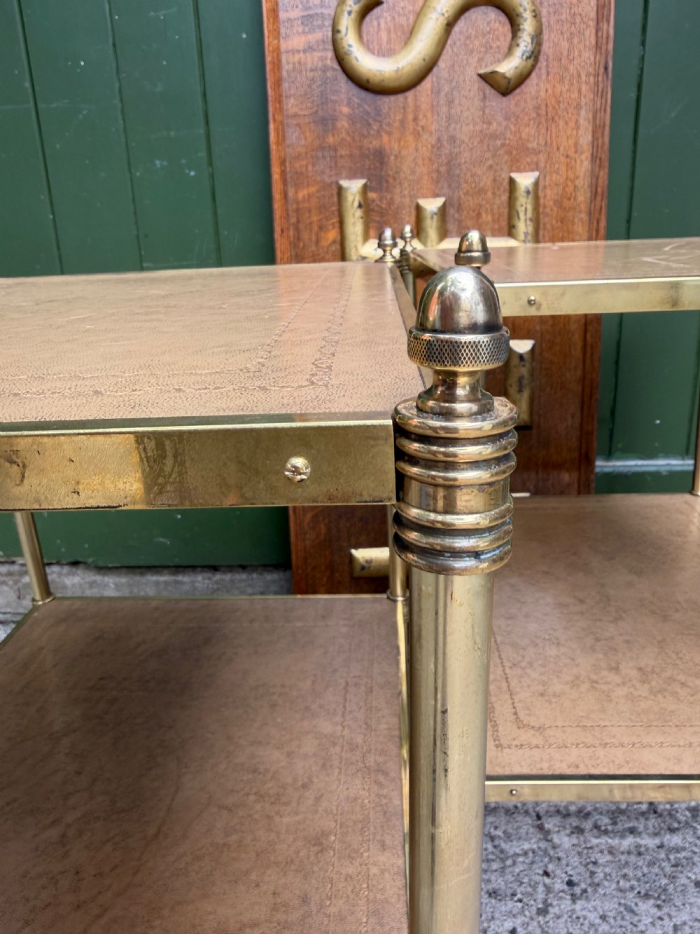 A pair of early twentieth-century two-tier lacquered brass etagere tables featuring inset tan tooled leather tops and turned brass corner posts. View X