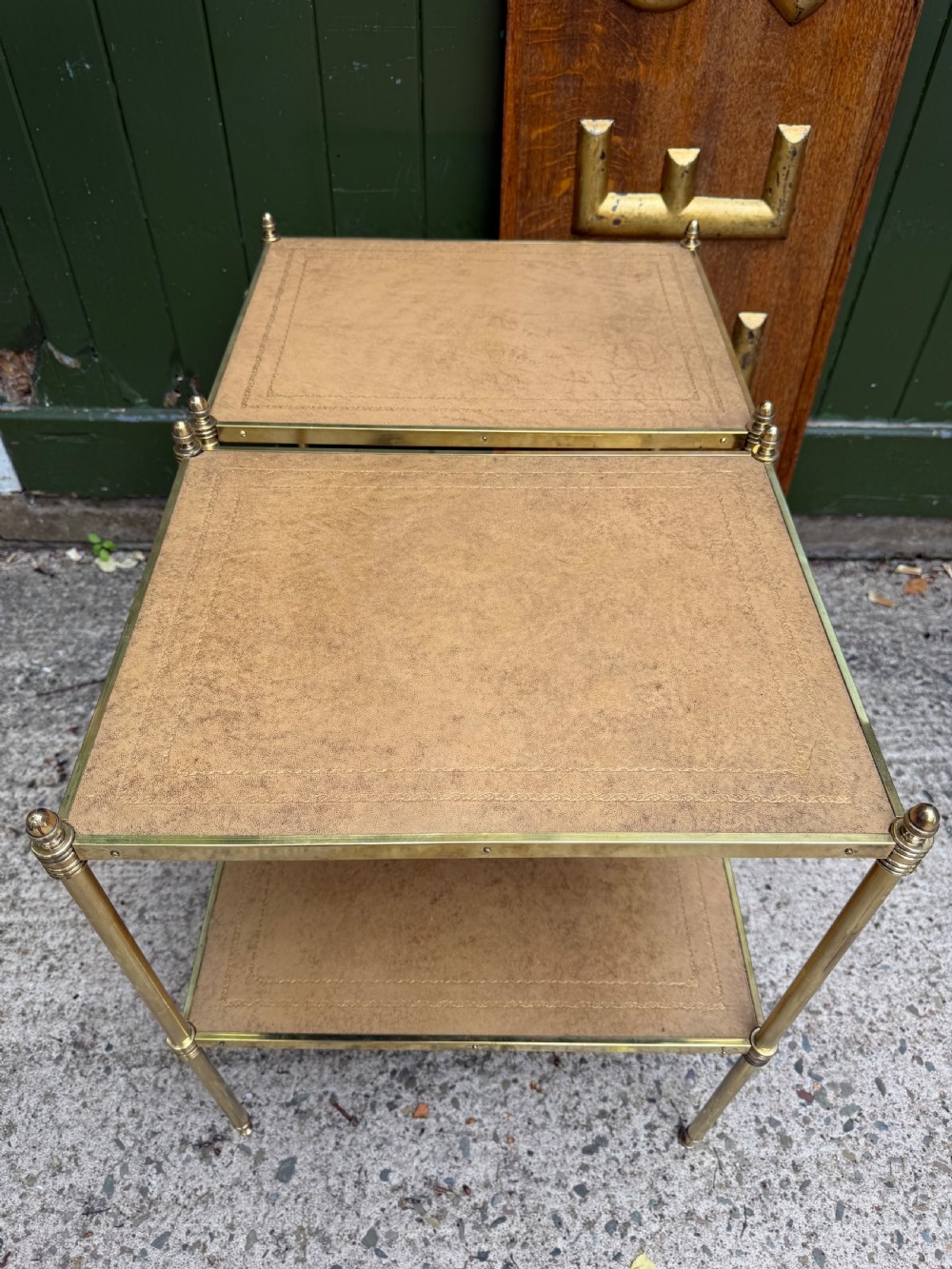 A pair of early twentieth-century two-tier lacquered brass etagere tables featuring inset tan tooled leather tops and turned brass corner posts. View XX