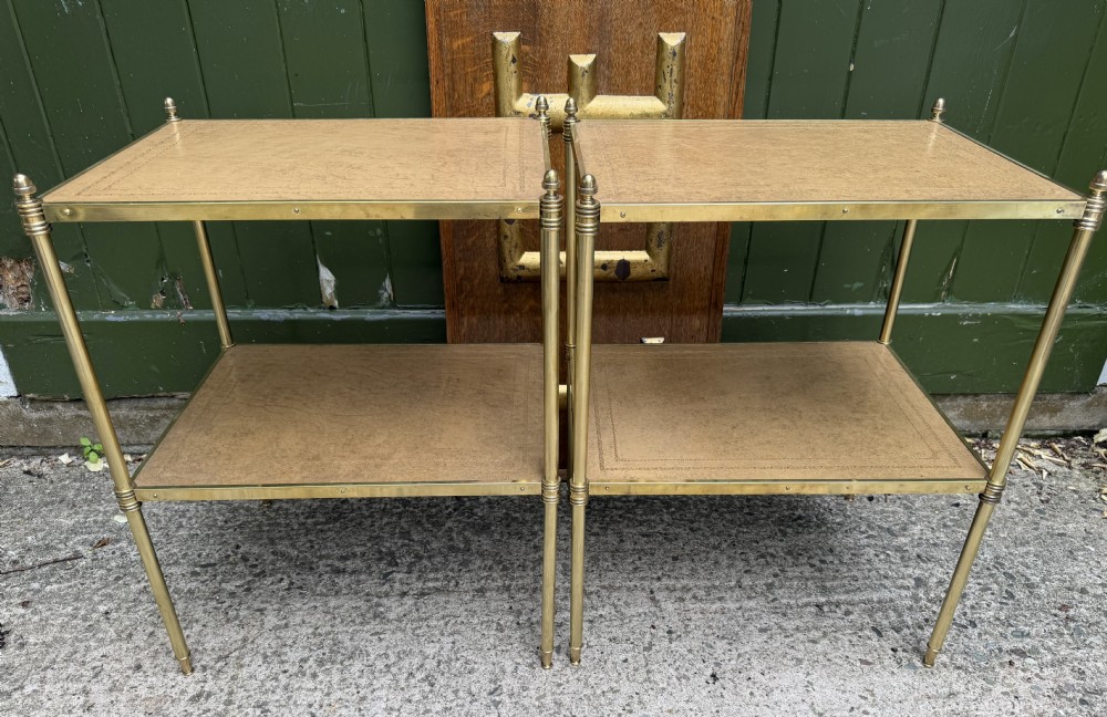 A pair of early twentieth-century two-tier lacquered brass etagere tables featuring inset tan tooled leather tops and turned brass corner posts. View II