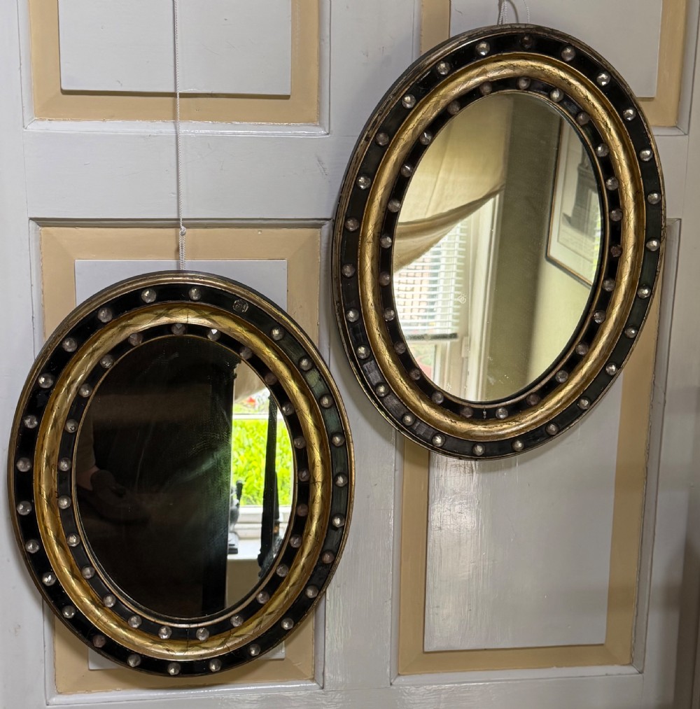 Scarce pair of early C19th Irish oval ebonised , parcel-gilt and glass cabochon mounted mirrors of smaller scale . View II