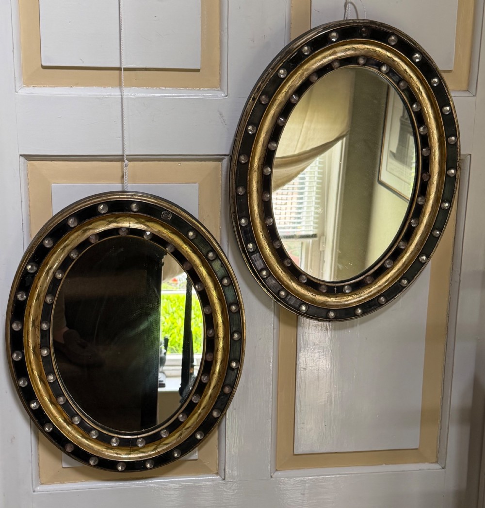 Scarce pair of early C19th Irish oval ebonised , parcel-gilt and glass cabochon mounted mirrors of smaller scale . View VI