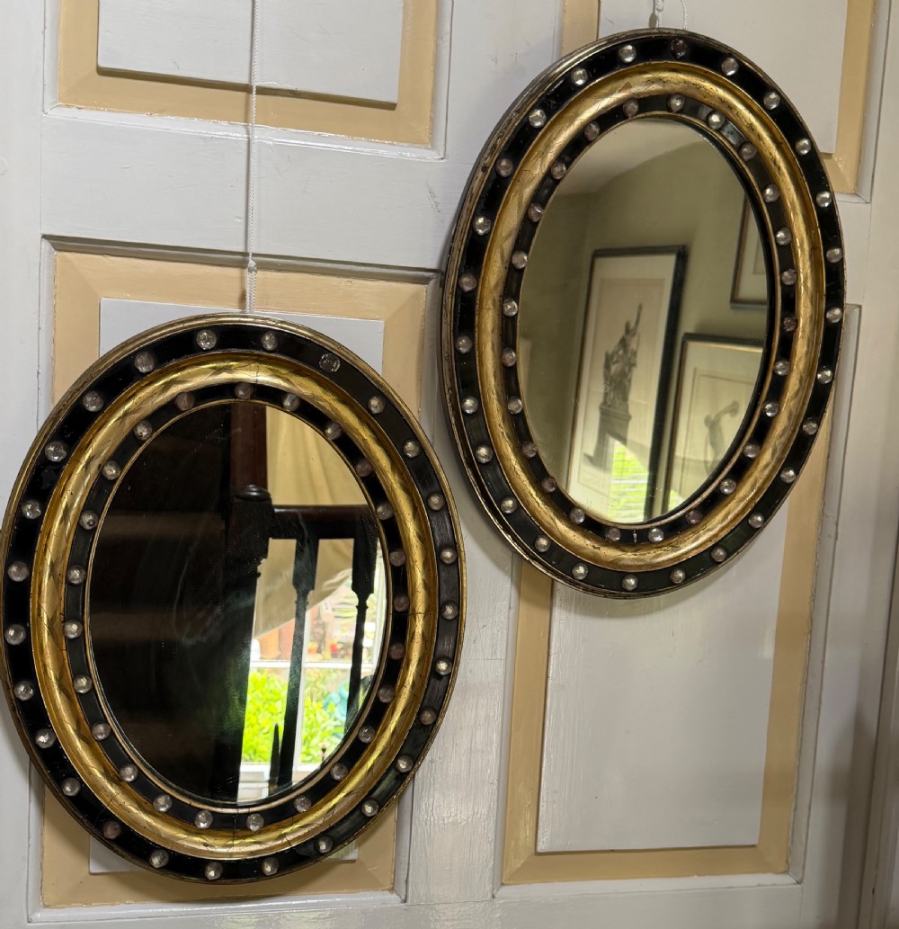 Scarce pair of early C19th Irish oval ebonised , parcel-gilt and glass cabochon mounted mirrors of smaller scale . View XI