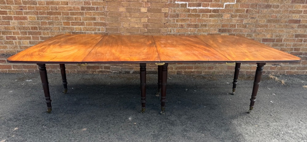 An early nineteenth-century Regency mahogany extending dining table featuring multiple drop-leaf sections and turned legs with brass castors.