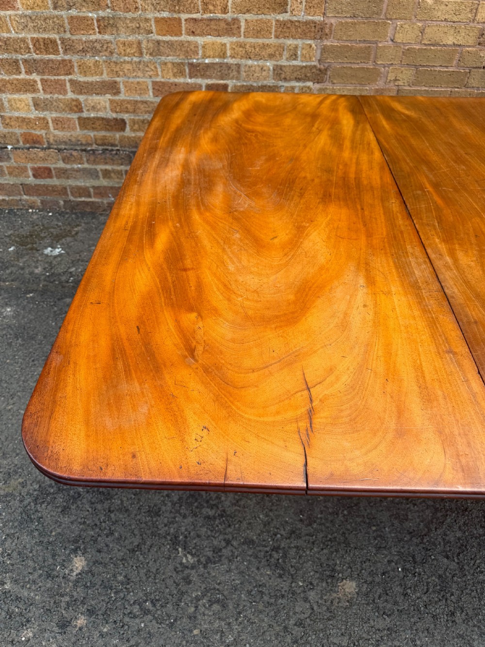An early nineteenth-century Regency mahogany extending dining table featuring multiple drop-leaf sections and turned legs with brass castors. View IX
