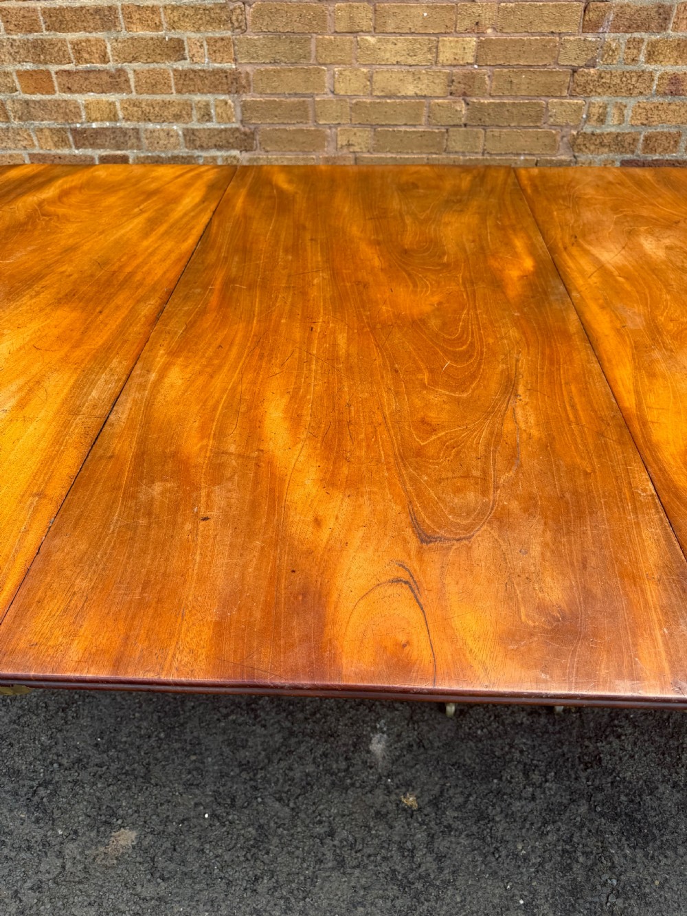 An early nineteenth-century Regency mahogany extending dining table featuring multiple drop-leaf sections and turned legs with brass castors. View X