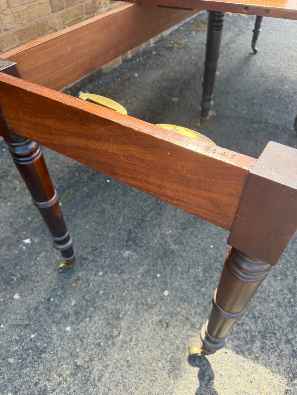 An early nineteenth-century Regency mahogany extending dining table featuring multiple drop-leaf sections and turned legs with brass castors. View XVI