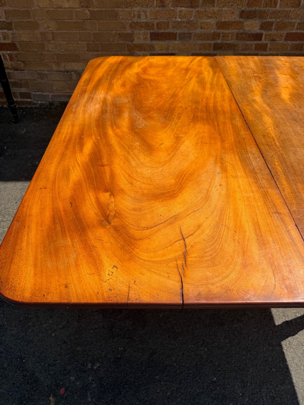 An early nineteenth-century Regency mahogany extending dining table featuring multiple drop-leaf sections and turned legs with brass castors. View XXI