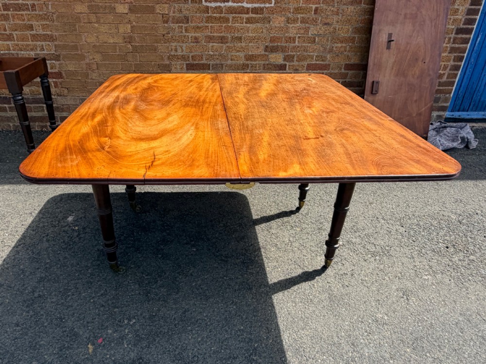 An early nineteenth-century Regency mahogany extending dining table featuring multiple drop-leaf sections and turned legs with brass castors. View XXIII