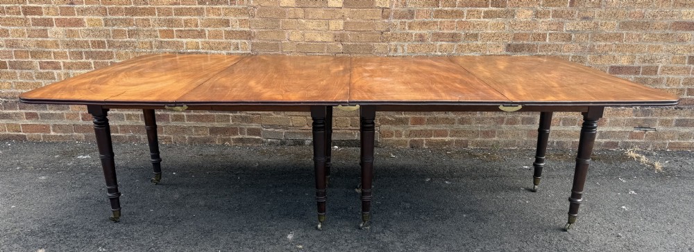 An early nineteenth-century Regency mahogany extending dining table featuring multiple drop-leaf sections and turned legs with brass castors. View XXVIII