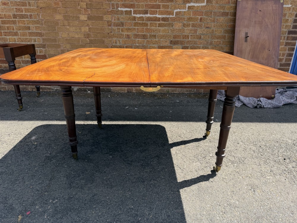 An early nineteenth-century Regency mahogany extending dining table featuring multiple drop-leaf sections and turned legs with brass castors. View XIX