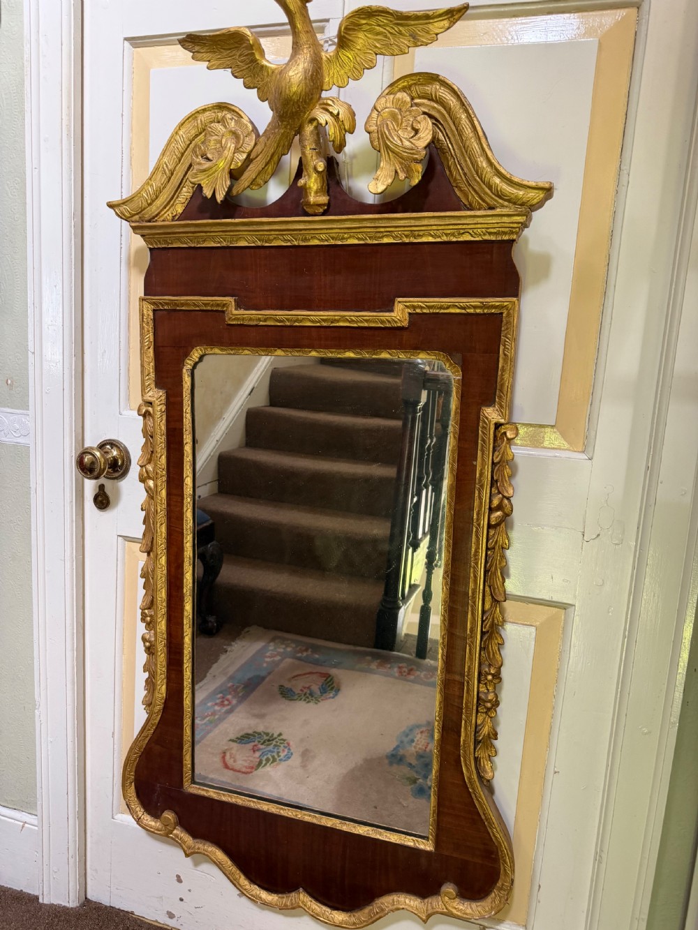 A nineteenth-century George II revival mahogany pier mirror featuring parcel-gilt mouldings, side foliage carvings, a broken pediment, and a carved eagle finial. View II