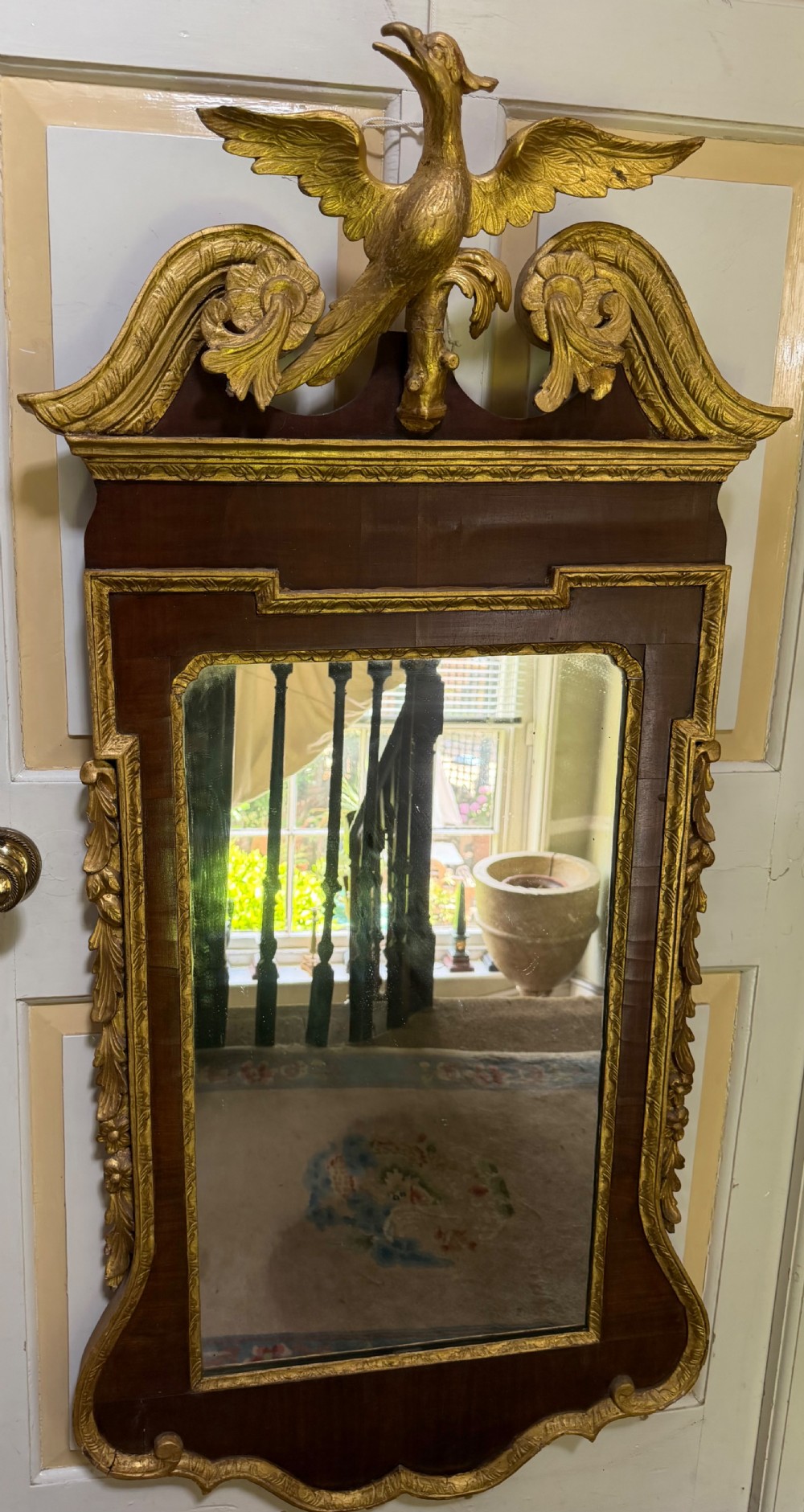 A nineteenth-century George II revival mahogany pier mirror featuring parcel-gilt mouldings, side foliage carvings, a broken pediment, and a carved eagle finial. View III